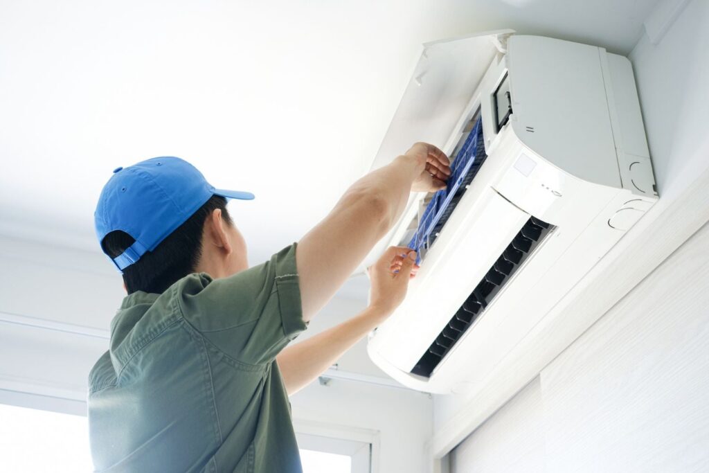 AC technician performing maintenance on a split AC unit in Dubai